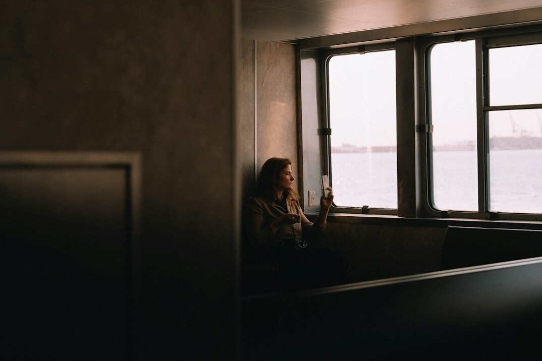 Young Brazilian woman with curly hair reading a book by a sunlit window